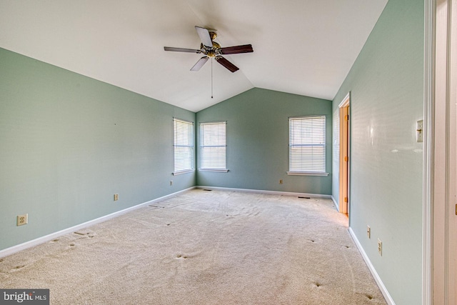 carpeted spare room featuring ceiling fan, vaulted ceiling, and baseboards