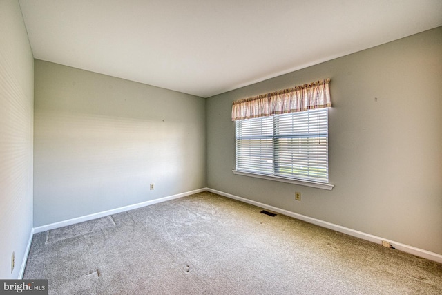 unfurnished room with carpet floors, visible vents, and baseboards