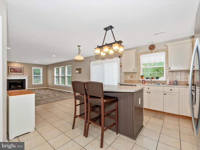 kitchen featuring white cabinets, visible vents, light countertops, and a center island