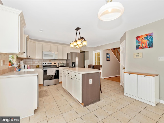 kitchen with a kitchen island, appliances with stainless steel finishes, light tile patterned flooring, a sink, and decorative backsplash