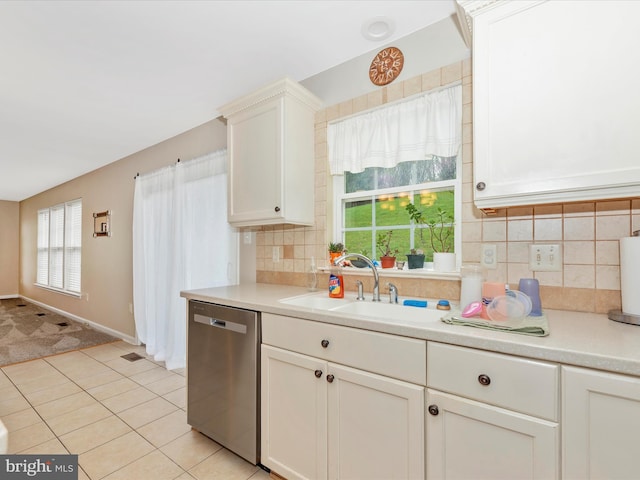 kitchen with a sink, backsplash, stainless steel dishwasher, and light countertops