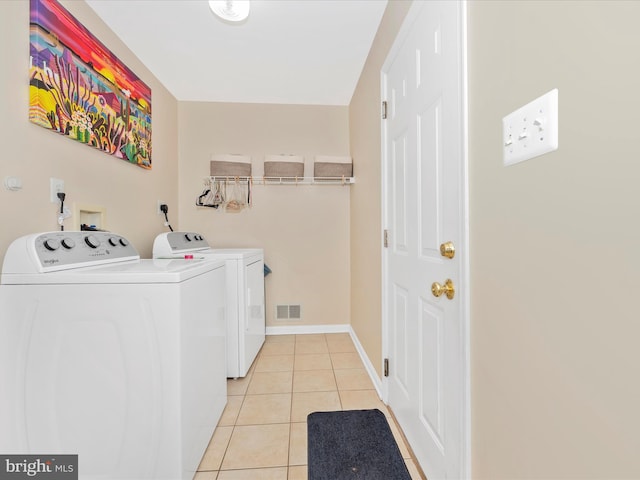 laundry room featuring baseboards, light tile patterned flooring, visible vents, laundry area, and washing machine and clothes dryer