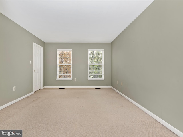 spare room featuring visible vents, baseboards, and light carpet