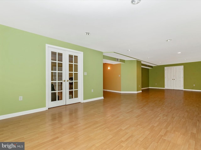 empty room with french doors, baseboards, light wood finished floors, and recessed lighting