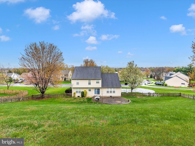 rear view of house featuring roof with shingles, a fenced backyard, and a lawn