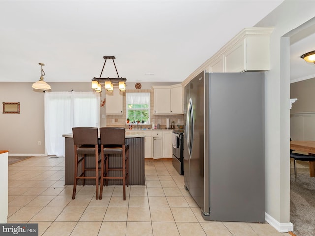 kitchen featuring tasteful backsplash, a breakfast bar, a center island, light countertops, and appliances with stainless steel finishes