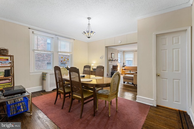 dining space with a textured ceiling, crown molding, dark wood-style floors, and a notable chandelier