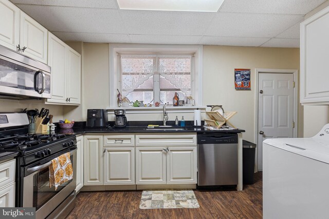 kitchen with dark wood-type flooring, washer / clothes dryer, stainless steel appliances, and a sink