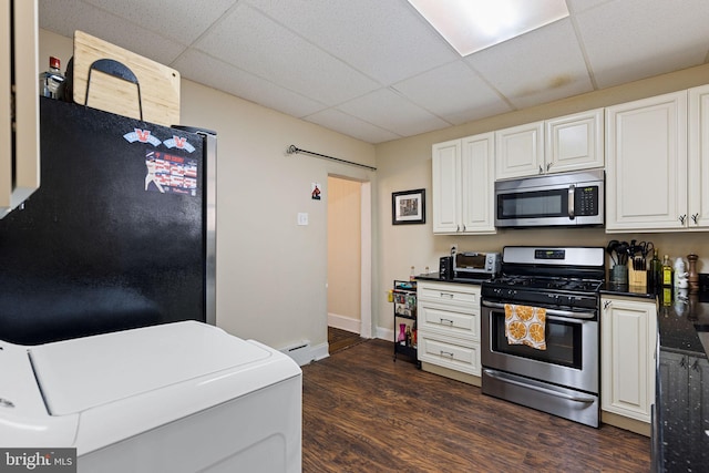 kitchen with dark wood-style flooring, a drop ceiling, dark countertops, white cabinetry, and appliances with stainless steel finishes