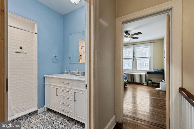 full bathroom with a ceiling fan, vanity, radiator, baseboards, and a shower with shower curtain