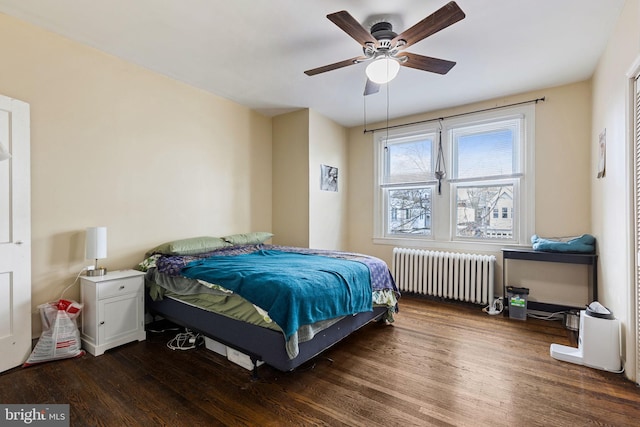 bedroom with dark wood-type flooring, radiator heating unit, and a ceiling fan