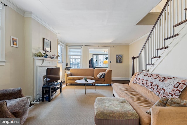carpeted living room with baseboards, a brick fireplace, stairway, and crown molding