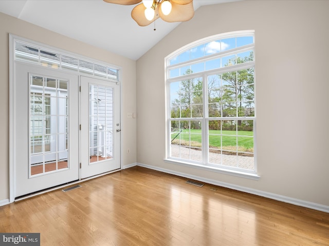 empty room featuring wood finished floors, vaulted ceiling, ceiling fan, and visible vents