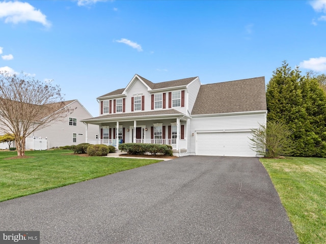 colonial inspired home featuring covered porch, a front yard, driveway, and an attached garage