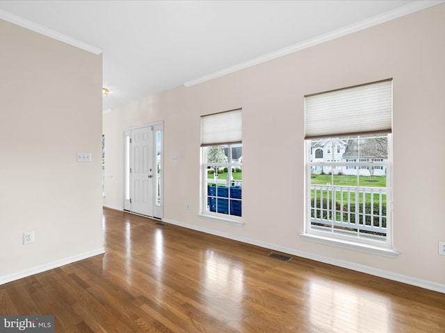foyer with visible vents, ornamental molding, and wood finished floors