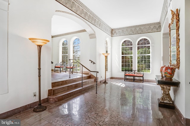 foyer with stairway, baseboards, arched walkways, and a towering ceiling
