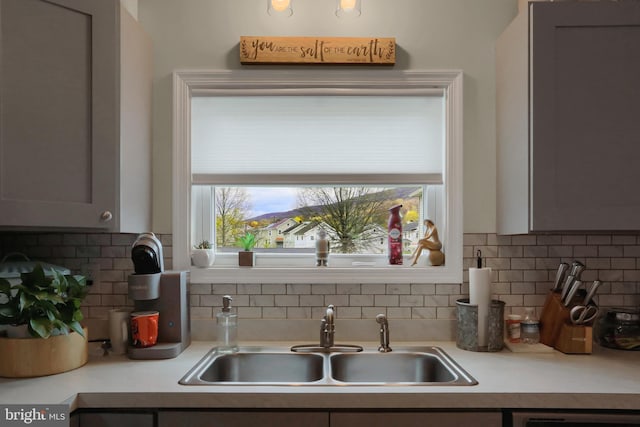 kitchen featuring light countertops, tasteful backsplash, and a sink
