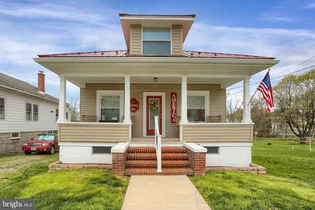 view of front of property featuring covered porch, a front yard, and metal roof