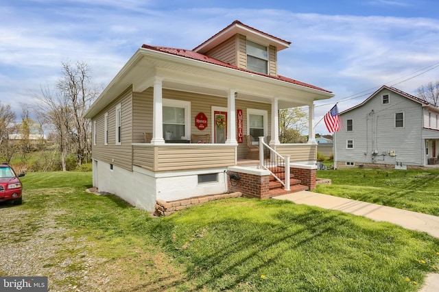 view of front of home featuring metal roof, a front lawn, and covered porch