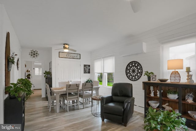 dining area featuring light wood-type flooring, plenty of natural light, a wall mounted AC, and ceiling fan