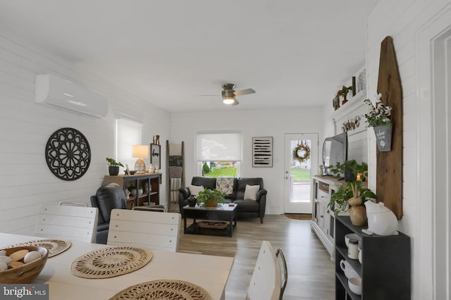 living area with ceiling fan, wood finished floors, and a wall unit AC