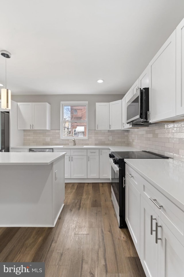 kitchen with dark wood finished floors, white cabinetry, and appliances with stainless steel finishes