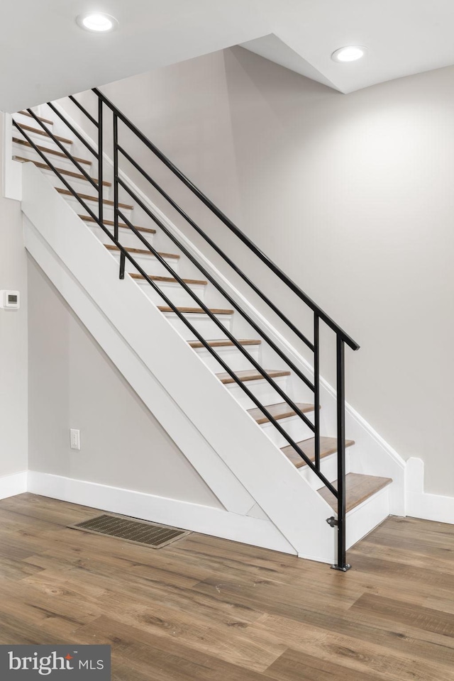 stairway featuring baseboards, visible vents, wood finished floors, and recessed lighting