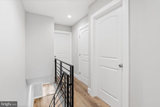 corridor featuring baseboards, an upstairs landing, recessed lighting, and light wood finished floors