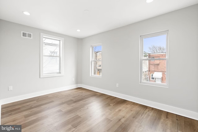 empty room with baseboards, wood finished floors, and a healthy amount of sunlight
