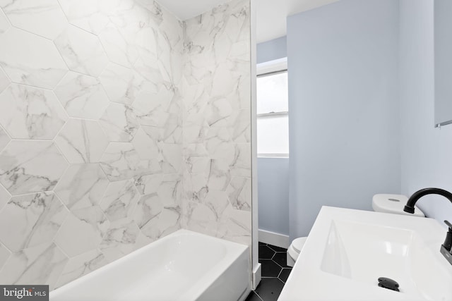 bathroom featuring baseboards, toilet, a sink, and shower / washtub combination