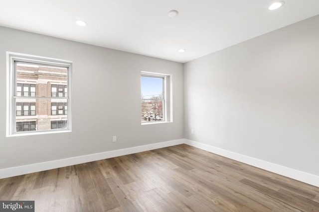 spare room featuring baseboards, wood finished floors, and recessed lighting