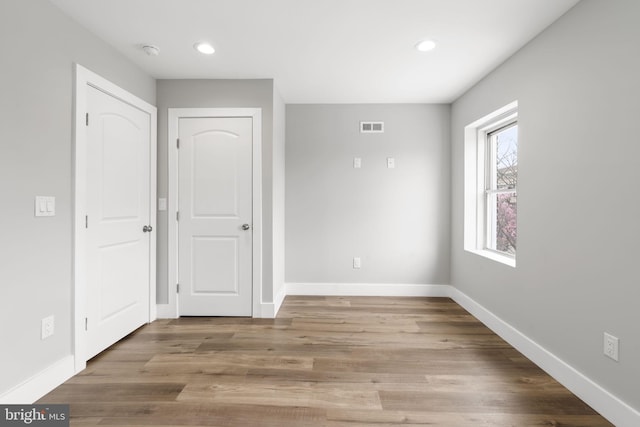 unfurnished bedroom featuring baseboards, visible vents, recessed lighting, and wood finished floors