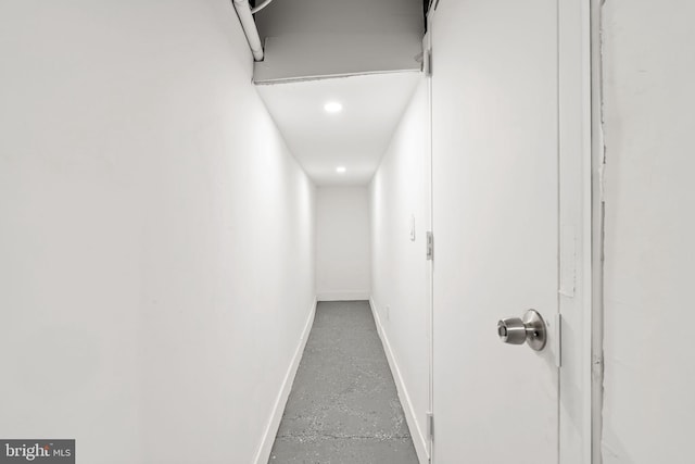 hall with baseboards and finished concrete floors