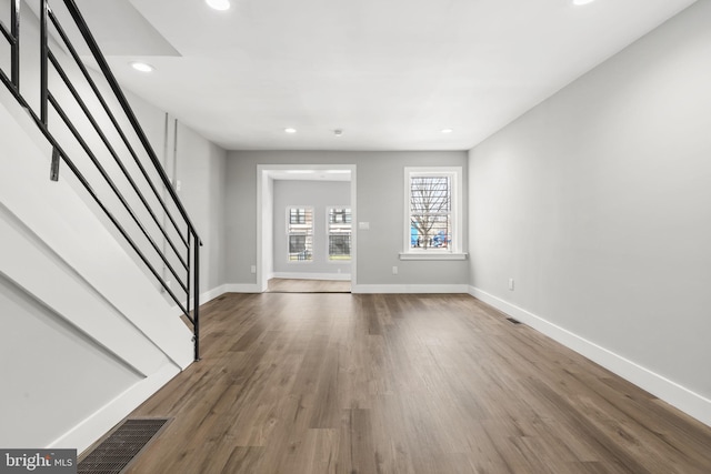unfurnished living room with stairs, wood finished floors, baseboards, visible vents, and recessed lighting