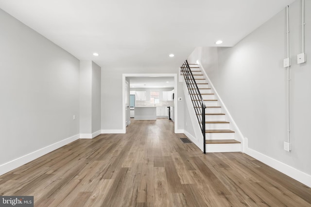 interior space with stairs, visible vents, wood finished floors, and baseboards