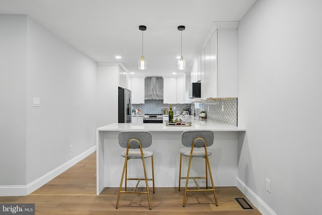 7434 Mason Ln, Falls Church, VA 22042 - kitchen with stainless steel appliances, wall chimney exhaust hood, a peninsula, tasteful backsplash, and white cabinetry