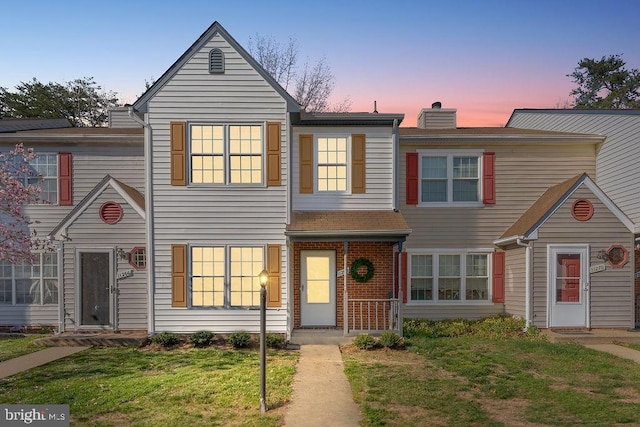 townhome / multi-family property featuring a yard and a chimney