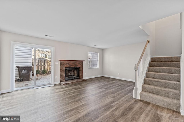 unfurnished living room with a wealth of natural light, visible vents, wood finished floors, and stairs