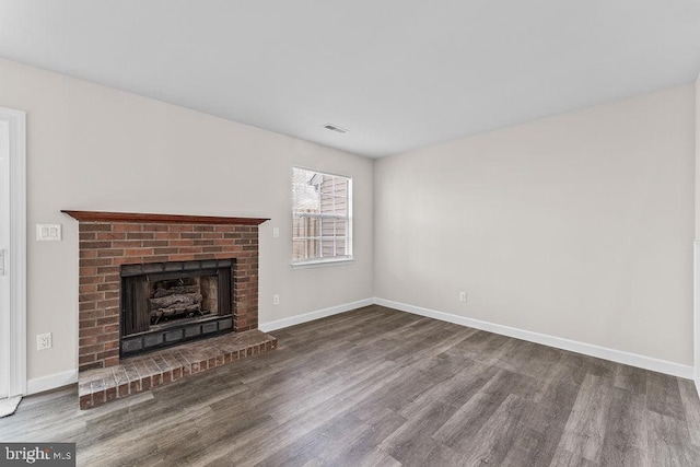 unfurnished living room with wood finished floors, baseboards, a fireplace, and visible vents