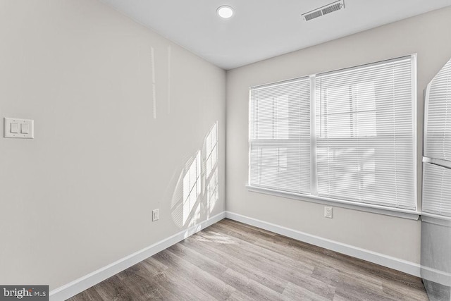 unfurnished room with wood finished floors, baseboards, and visible vents