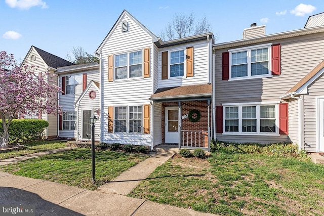 townhome / multi-family property featuring a front lawn, a chimney, and brick siding