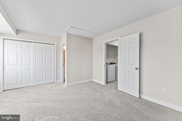 unfurnished bedroom with a closet, baseboards, washer / clothes dryer, attic access, and light carpet