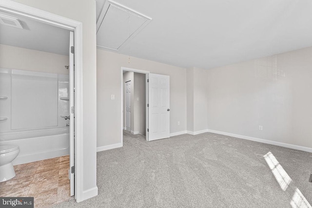unfurnished bedroom with attic access, baseboards, and carpet