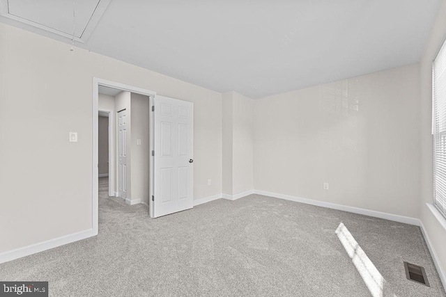 spare room with carpet floors, baseboards, attic access, and visible vents