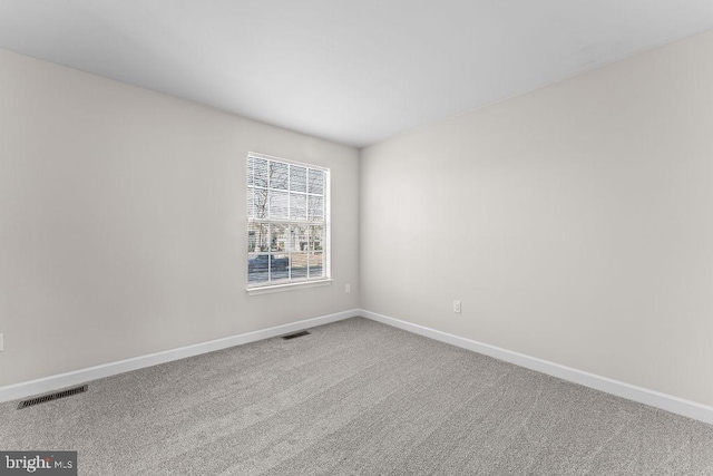 carpeted empty room featuring baseboards and visible vents