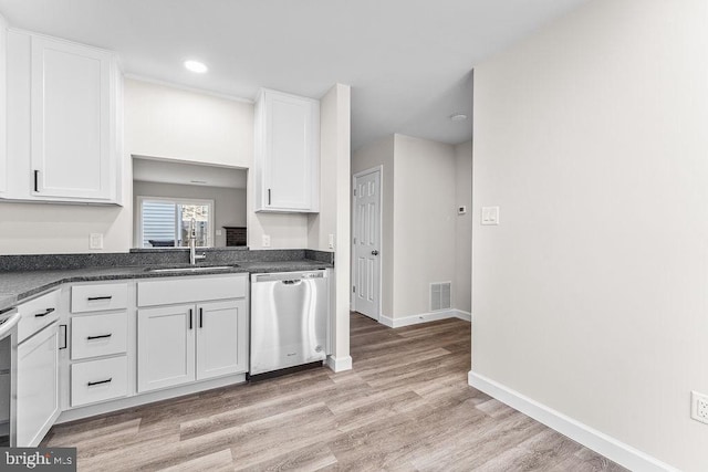 kitchen with a sink, dark countertops, visible vents, light wood-style flooring, and appliances with stainless steel finishes