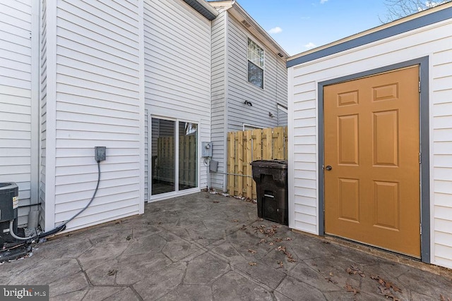 view of exterior entry featuring fence and a patio area