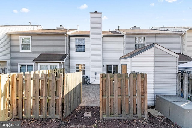 rear view of property featuring central air condition unit, fence, and a chimney