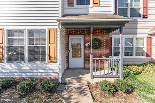 property entrance featuring covered porch and brick siding