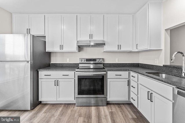 kitchen with a sink, white cabinets, under cabinet range hood, and appliances with stainless steel finishes